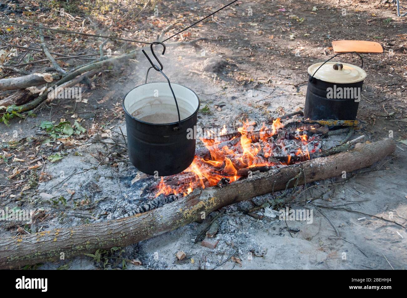 Rußiger Topf mit kochender Suppe, die über dem Lagerfeuer an einem Draht  hängt. Camping im Freien Kochen, Überleben in der Wildnis Stockfotografie -  Alamy