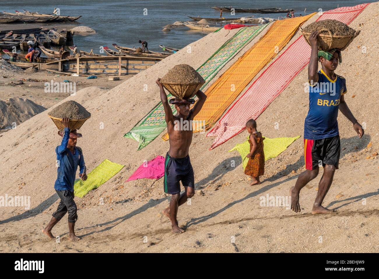 Arbeiter mit Körben, die den Schotter tragen, gruben aus dem Goyain-Fluss in Jaflong, an der Grenze zu Indien. Der Kies wird zu Beton gesiebt. Stockfoto