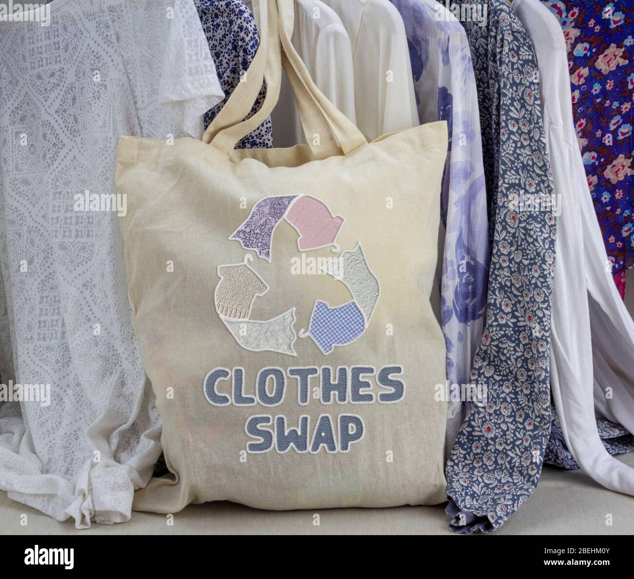 Kleidung tauschen wiederverwendbare Tasche mit genähten Recycling-Textilien Symbol vor dem Rack der Kleidung. Recyceln Sie Kleidung für ein nachhaltiges Leben. Stockfoto