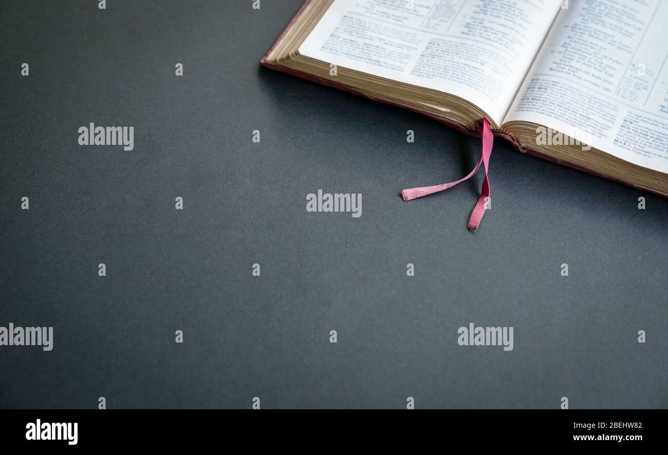 Draufsicht der offenen Bibel auf dem schwarzen Farbtisch. Leerzeichen für Text. Stockfoto