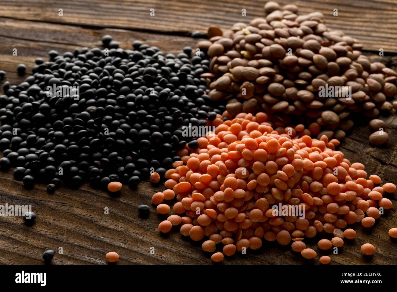 Verschiedene verschiedene Linsen mischen sich mit roten, braunen und schwarzen Beluga Linsen auf braunem Holztischhintergrund - selektiver Fokus Stockfoto