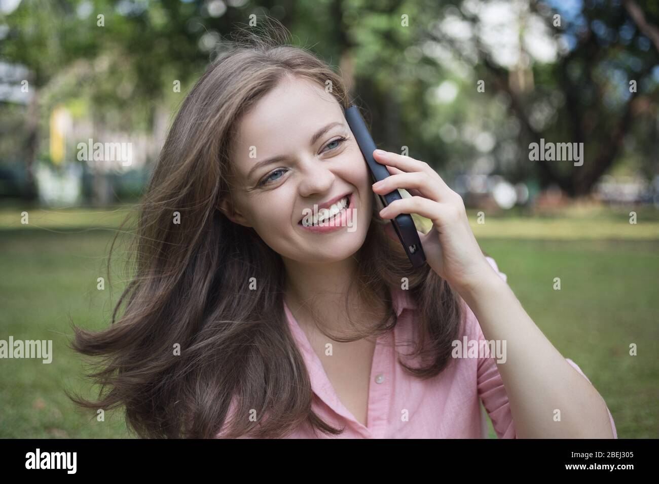 Lächelnd blonde junge kaukasische Frau Mädchen am Telefon im Park reden Stockfoto