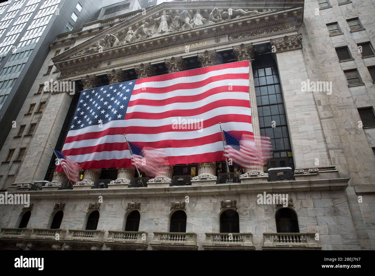 New York, USA. April 2020. Die US-Nationalflaggen werden vor der New York Stock Exchange (NYSE) in New York, USA, am 13. April 2020 von Windböen geblasen. Starker Wind und Regen trafen New York am Montag. Kredit: Michael Nagle/Xinhua/Alamy Live News Stockfoto