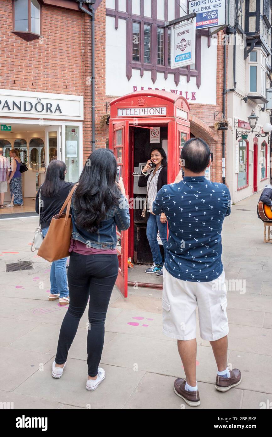 Tourist posiert für Fotos in ikonischen britischen Telefonkasten Stockfoto