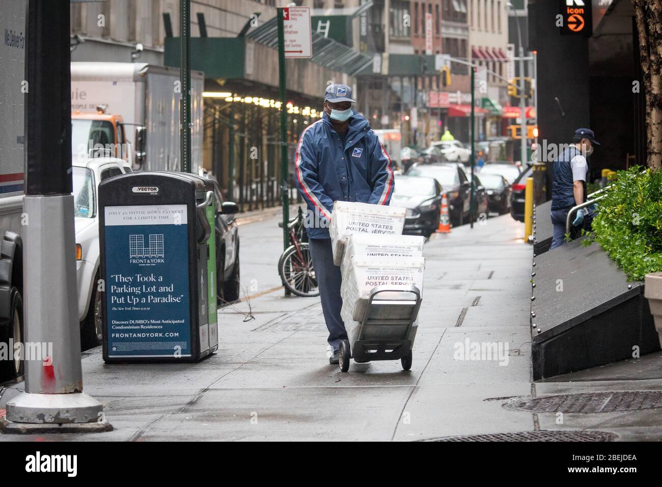 New York, USA. April 2020. Ein Mitarbeiter der United States Postal Service (USPS), der eine Maske trägt, liefert während der COVID-19-Pandemie in New York, USA, am 13. April 2020, Mails. Der Gouverneur des US-Bundesstaates New York Andrew Cuomo erließ eine Anordnung, die die Arbeitgeber anwies, wichtige Arbeiter mit Stoffen oder chirurgischen Masken zu versorgen, die sie tragen sollten, wenn sie direkt mit der Öffentlichkeit interagieren. Kredit: Michael Nagle/Xinhua/Alamy Live News Stockfoto