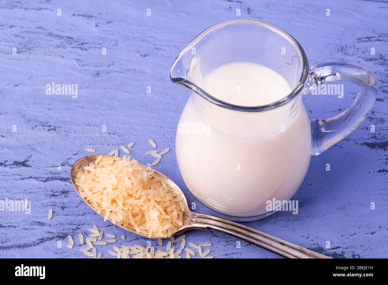 Auf dem hellblauen Holztisch, Reissamen und Reismilch im Krug im Vordergrund Stockfoto