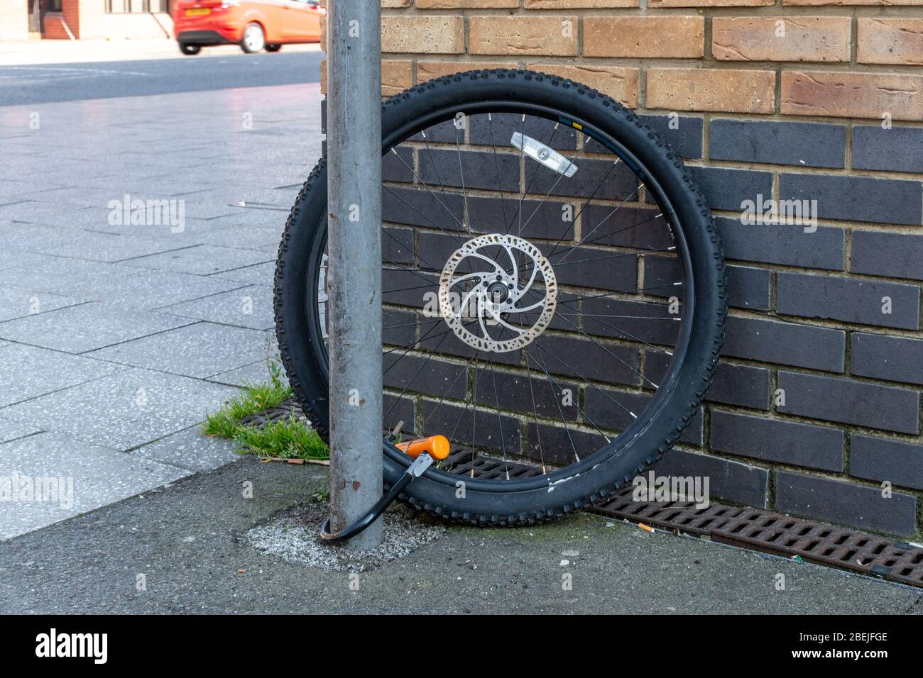 Ein einzelnes Rad, das nach dem Rest des Fahrrads an einen Pfosten gekettet wurde, wurde gestohlen. Fahrrad Diebstahl oder Kriminalität Konzept. Stockfoto