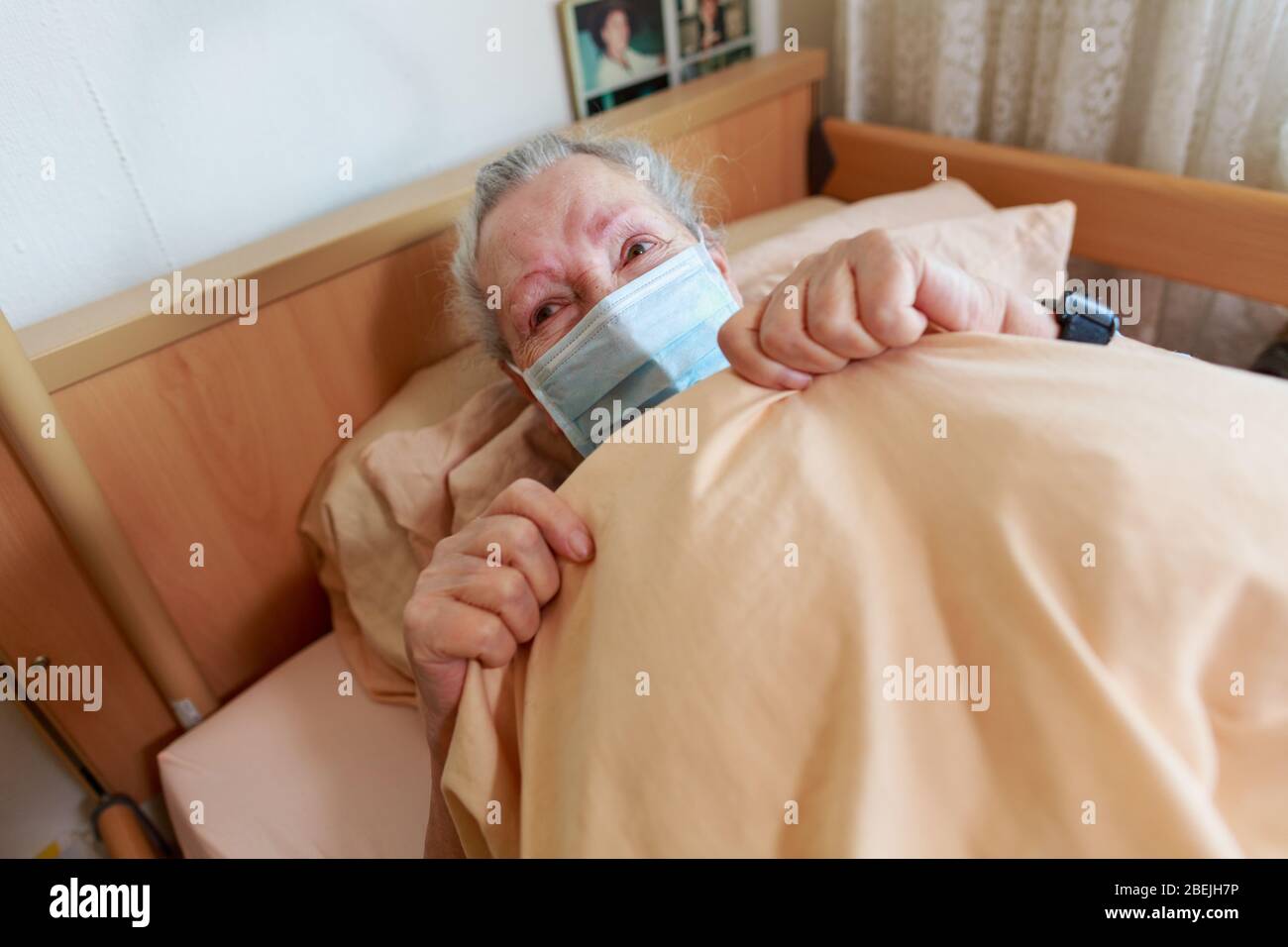 Eine alte Frau liegt mit einer Gesichtsmaske in ihrem Bett Stockfoto