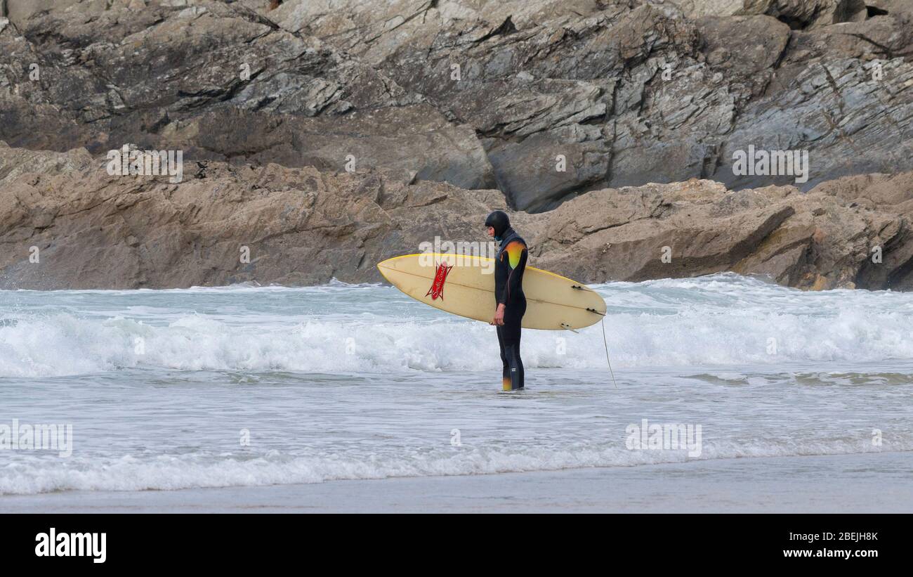 Ein Panoramabild eines Surfers, der am Fistral Beach in Newquay in Cornwall in der Hand seines Surfbretts steht und in Gedanken verloren geht. Stockfoto