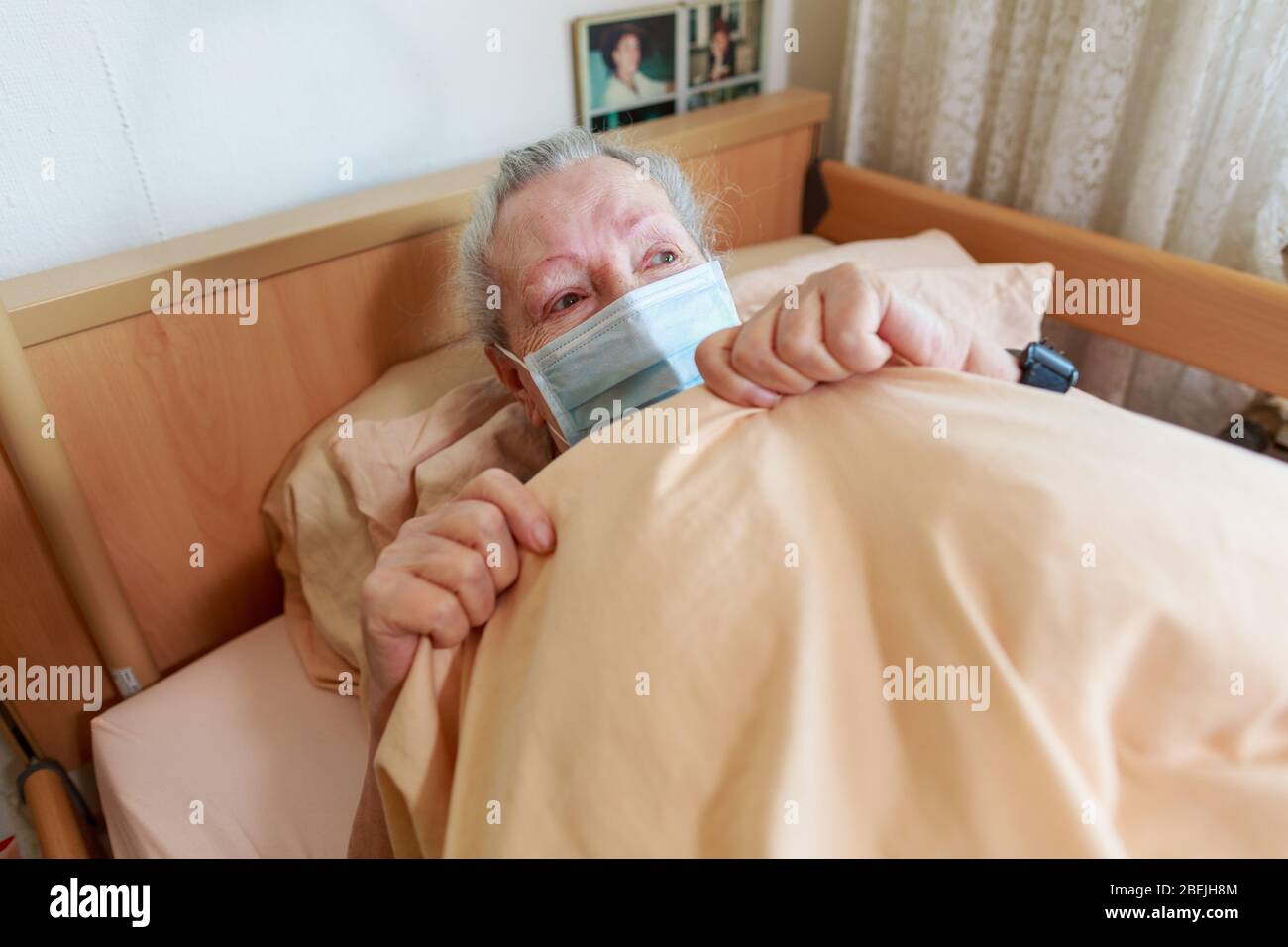 Eine alte Frau liegt mit einer Gesichtsmaske in ihrem Bett Stockfoto