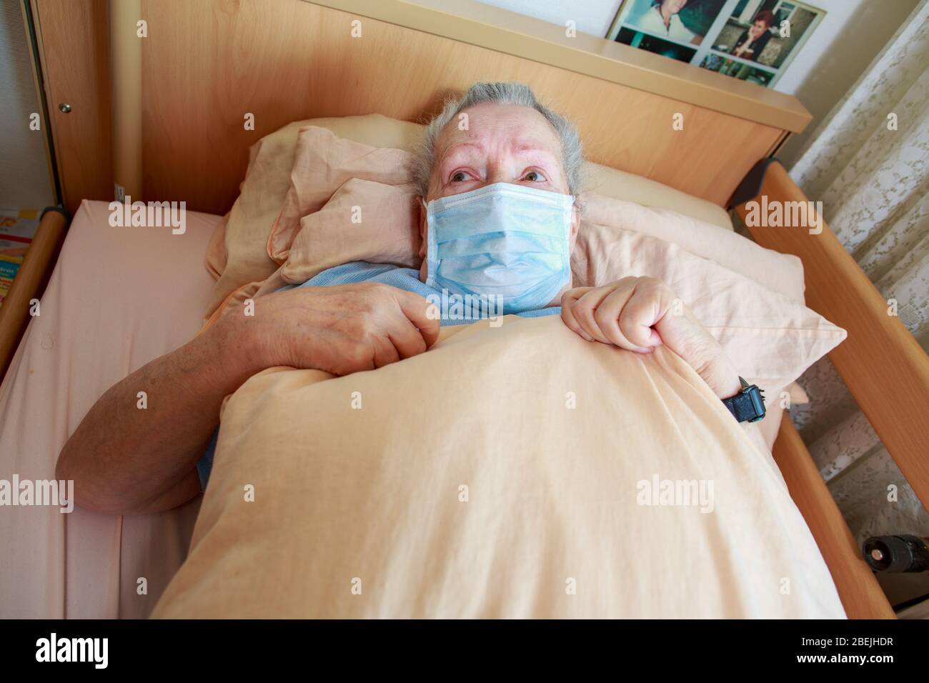 Eine alte Frau liegt mit einer Gesichtsmaske in ihrem Bett Stockfoto