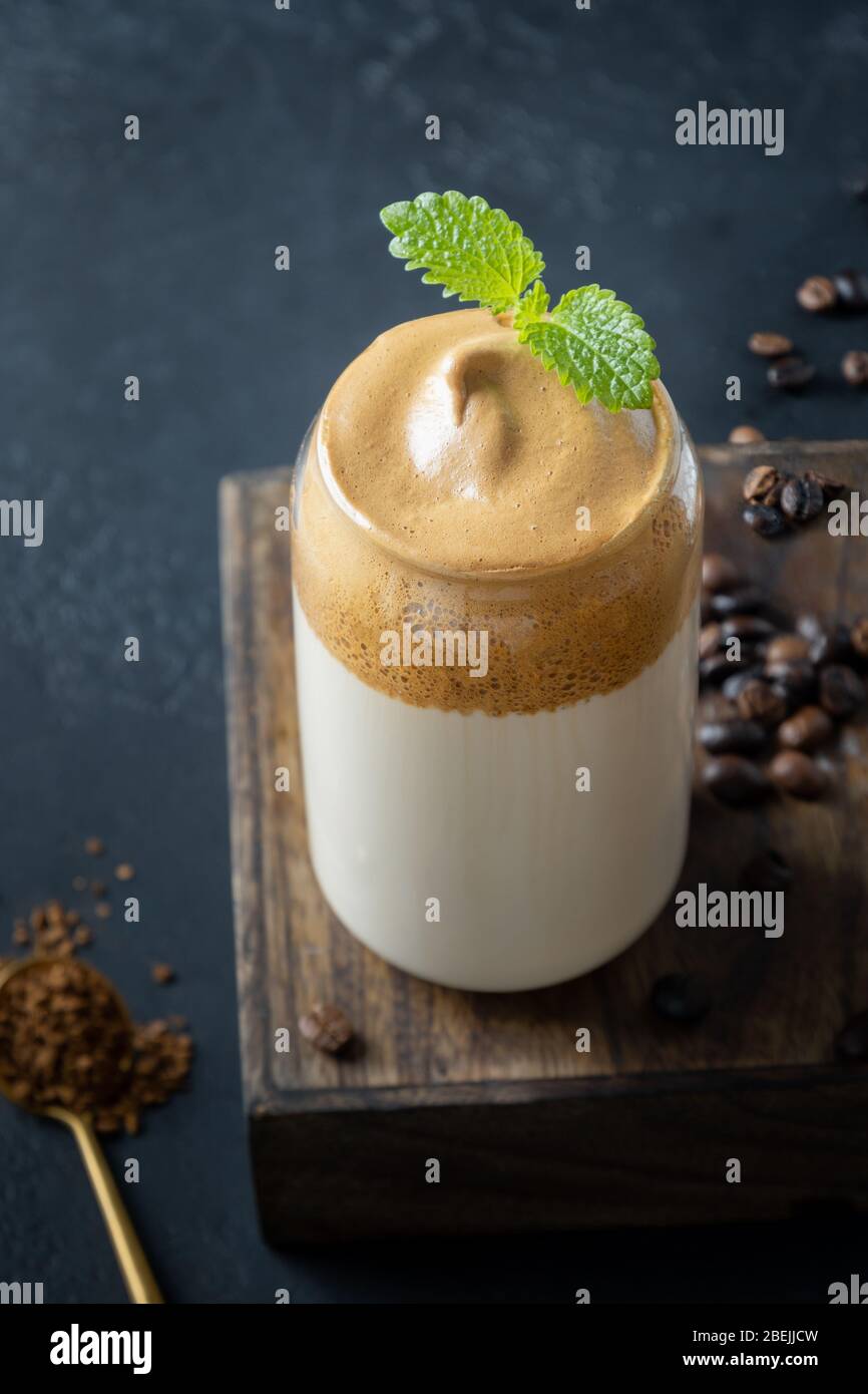 Dalgona schaumig Kaffee im Glas auf dunkel. Trend koreanischen Drink Latte Espresso mit Schaum von Instant-Kaffee. Vertikale Aufnahme. Stockfoto