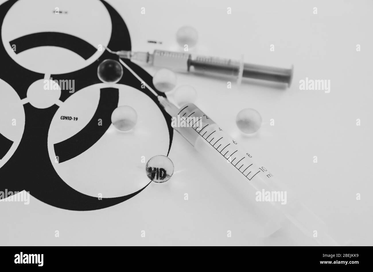 Covid-19-Impfstoff. Suche nach einem weltweiten Pandemimpfstoff. Spritzen mit medizinischer Substanz auf dem Hintergrund des Biohazard-Symbols. Stockfoto