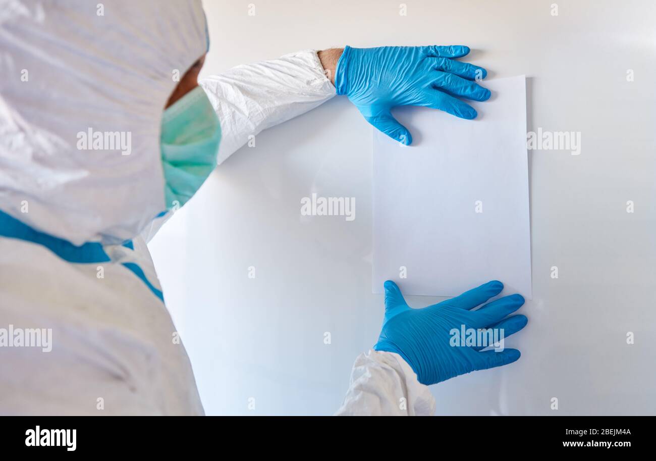 Medizinische Fachkräfte in Schutzkleidung hängen Informationen über das Verbot von Besuchen und das Verbot des Kontakts in der Klinik bei der Coronavirus-Epidemie Stockfoto