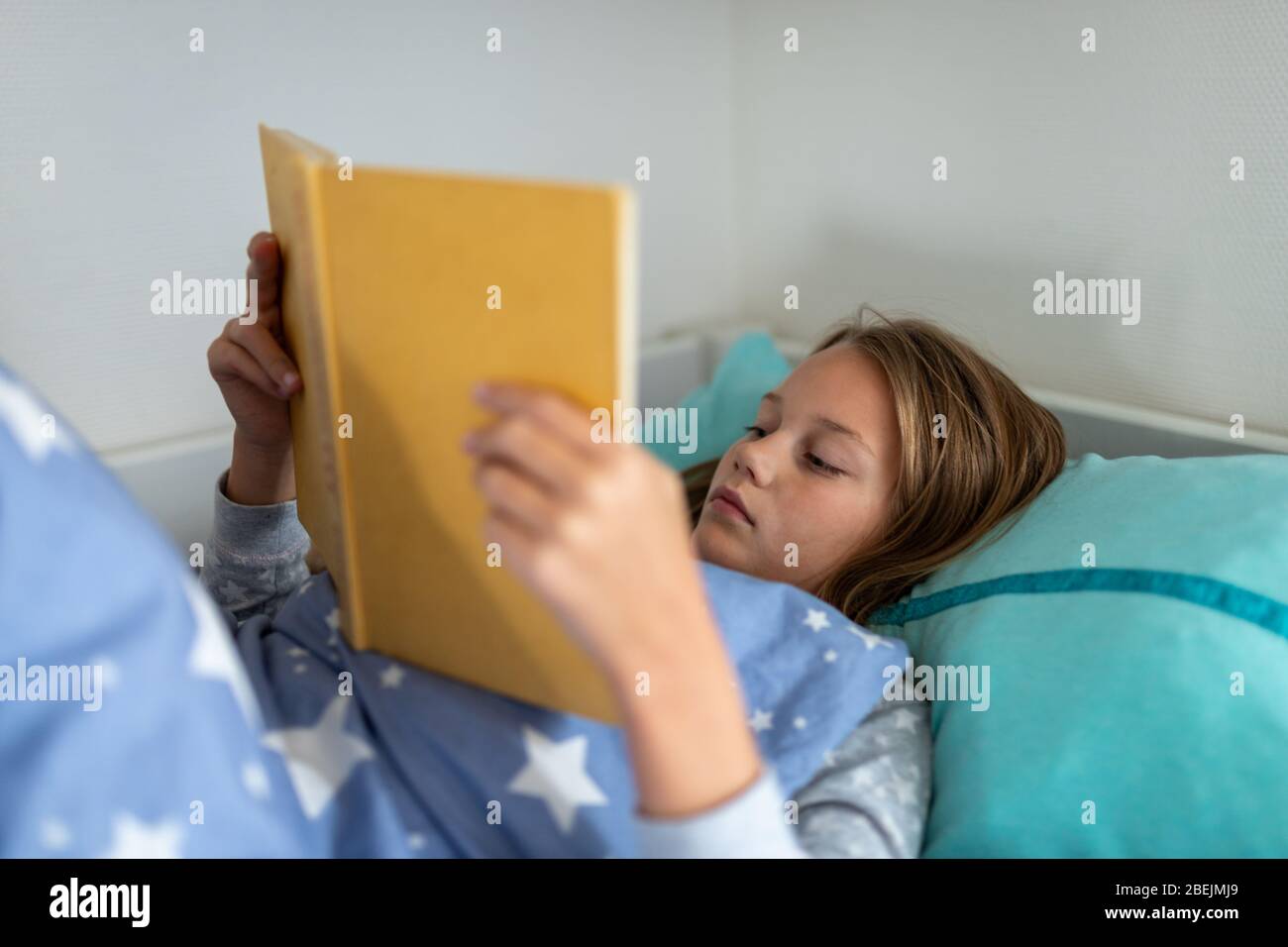 Mädchen liest ein Buch im Bett Stockfoto