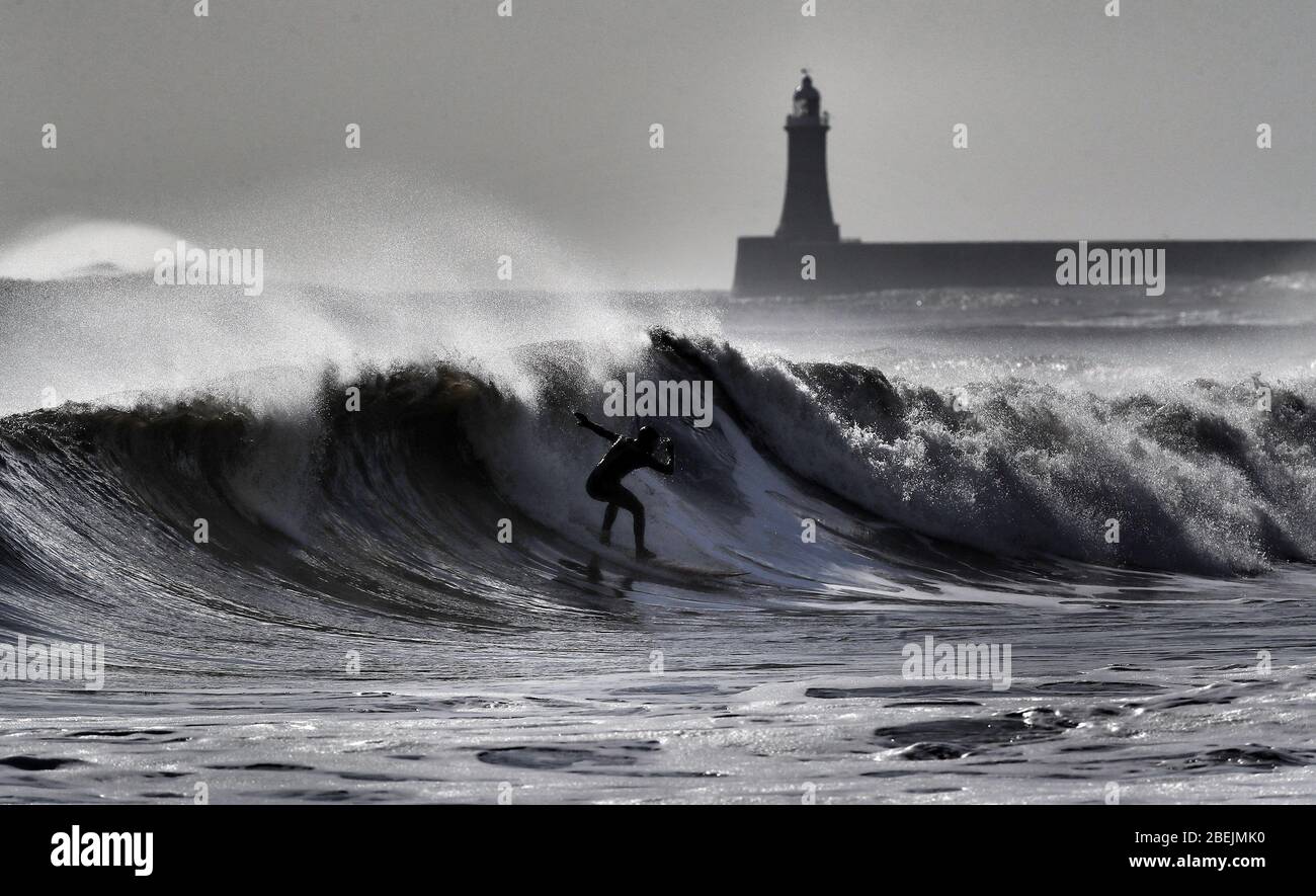 Ein Surfer reitet eine Welle vor der Nordostküste bei Tynemouth. Stockfoto