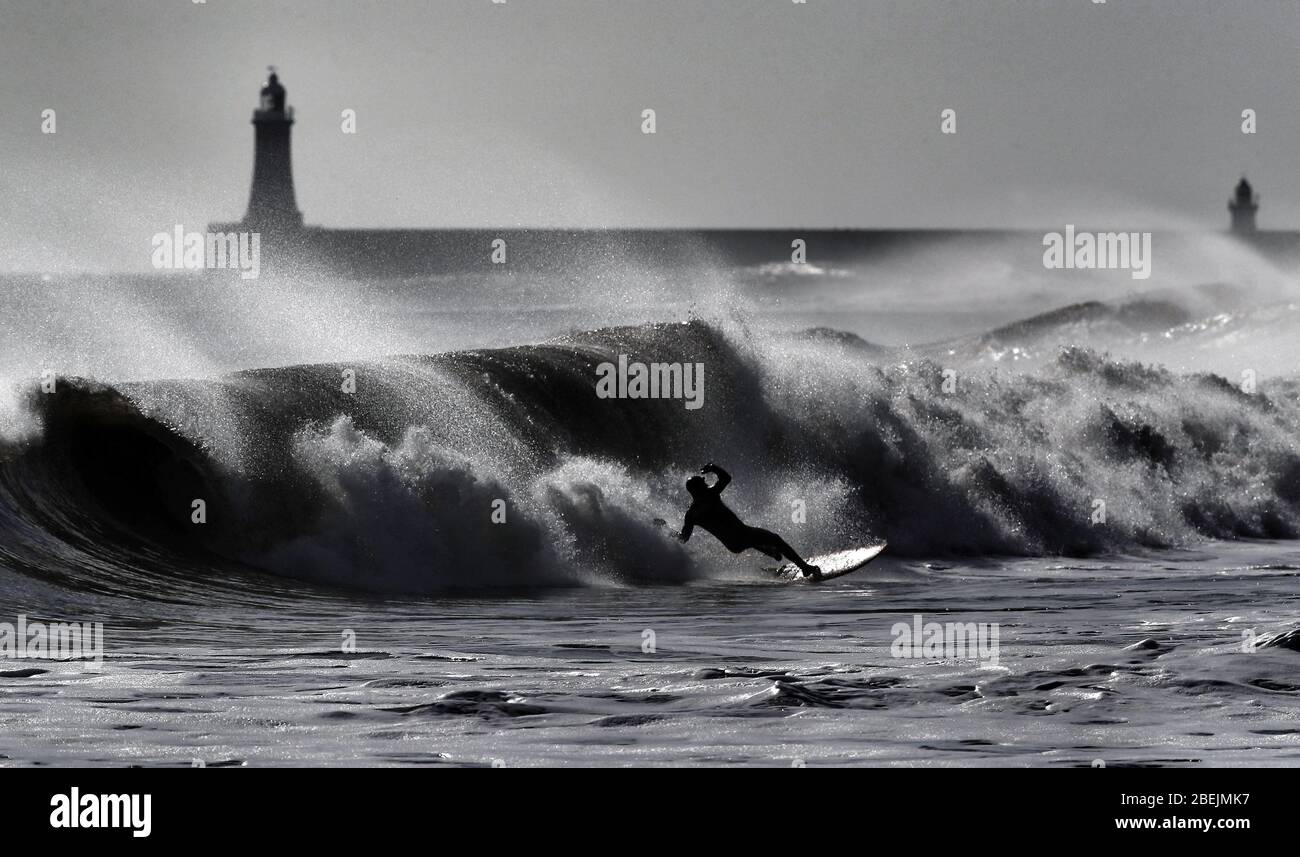 Ein Surfer reitet eine Welle vor der Nordostküste bei Tynemouth. Stockfoto