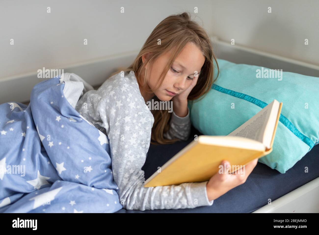 Mädchen-Lesebuch im Bett Stockfoto