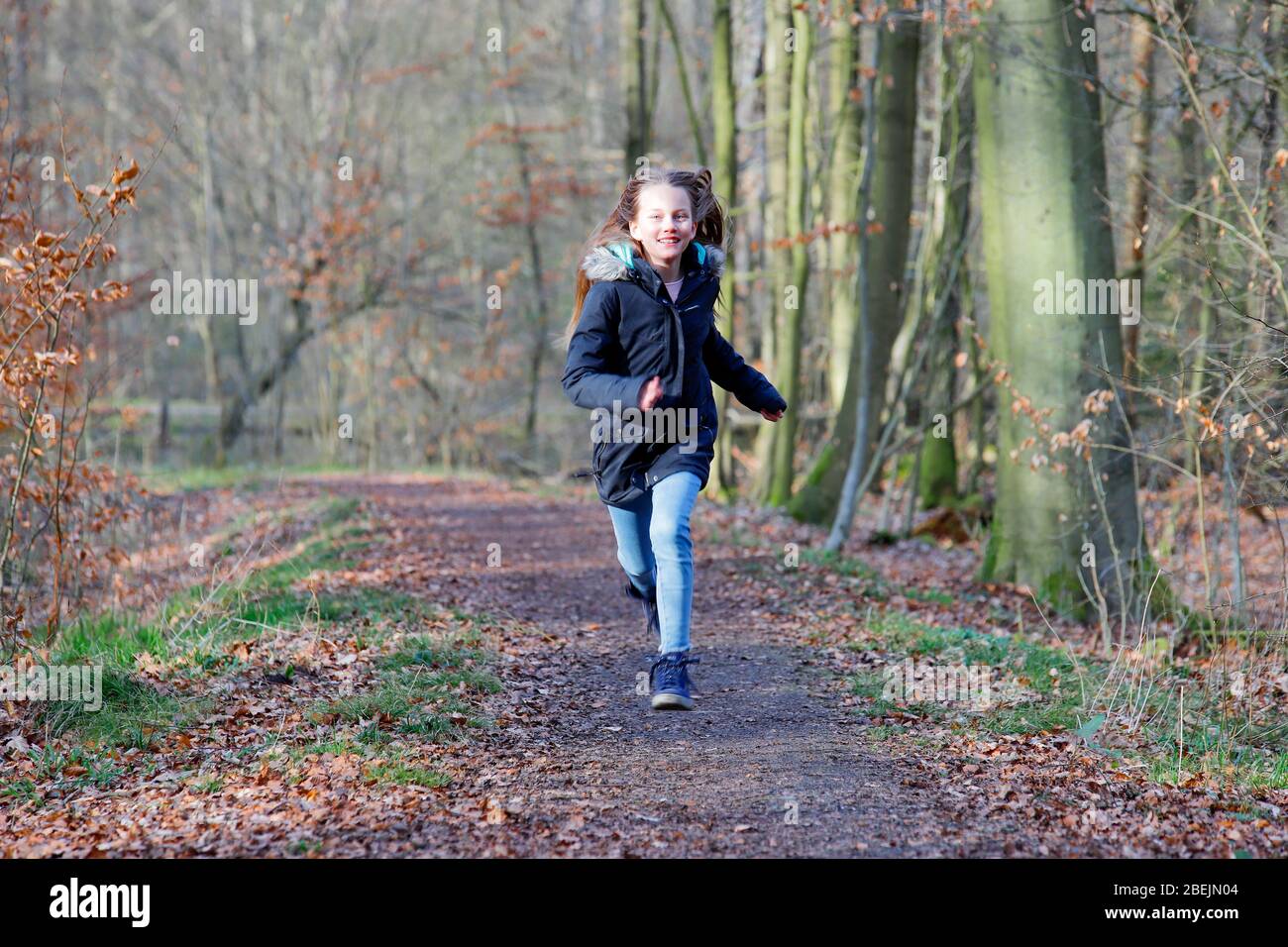 Ein Mädchen läuft auf einem Pfad im Wald Stockfoto