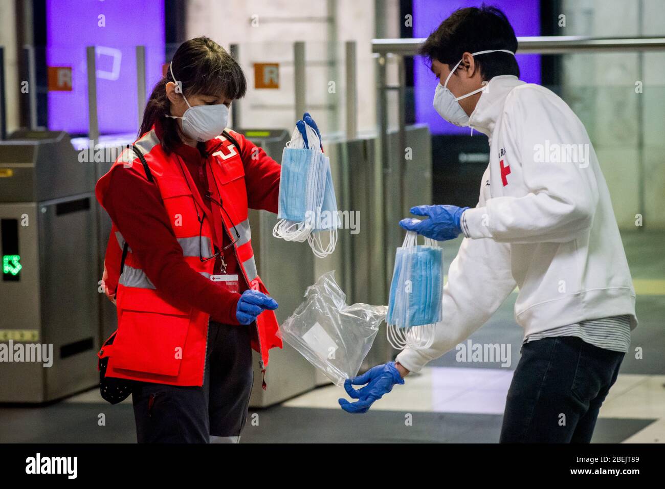 Barcelona, Katalonien, Spanien. 14. Apr 2020 - Freiwillige des Roten Kreuzes halten schützende Gesichtsmasken, um sie an der Station Catalunya in Barcelona unter Pendlern zu verteilen. Tausende von Menschen kehren zur Arbeit zurück, nachdem die spanische Regierung die strengsten Maßnahmen der Coronavirus-Haft aufzuheben hat. Quelle: Jordi Boixareu/Alamy Live News Stockfoto