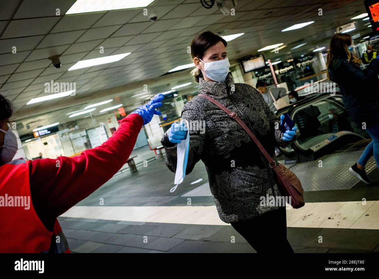 Barcelona, Katalonien, Spanien. 14. Apr 2020 - EIN Freiwilliger des Roten Kreuzes verteilt Schutzmaske unter Pendlern am Bahnhof Catalunya in Barcelona. Tausende von Menschen kehren zur Arbeit zurück, nachdem die spanische Regierung die strengsten Maßnahmen der Coronavirus-Haft aufzuheben hat. Quelle: Jordi Boixareu/Alamy Live News Stockfoto