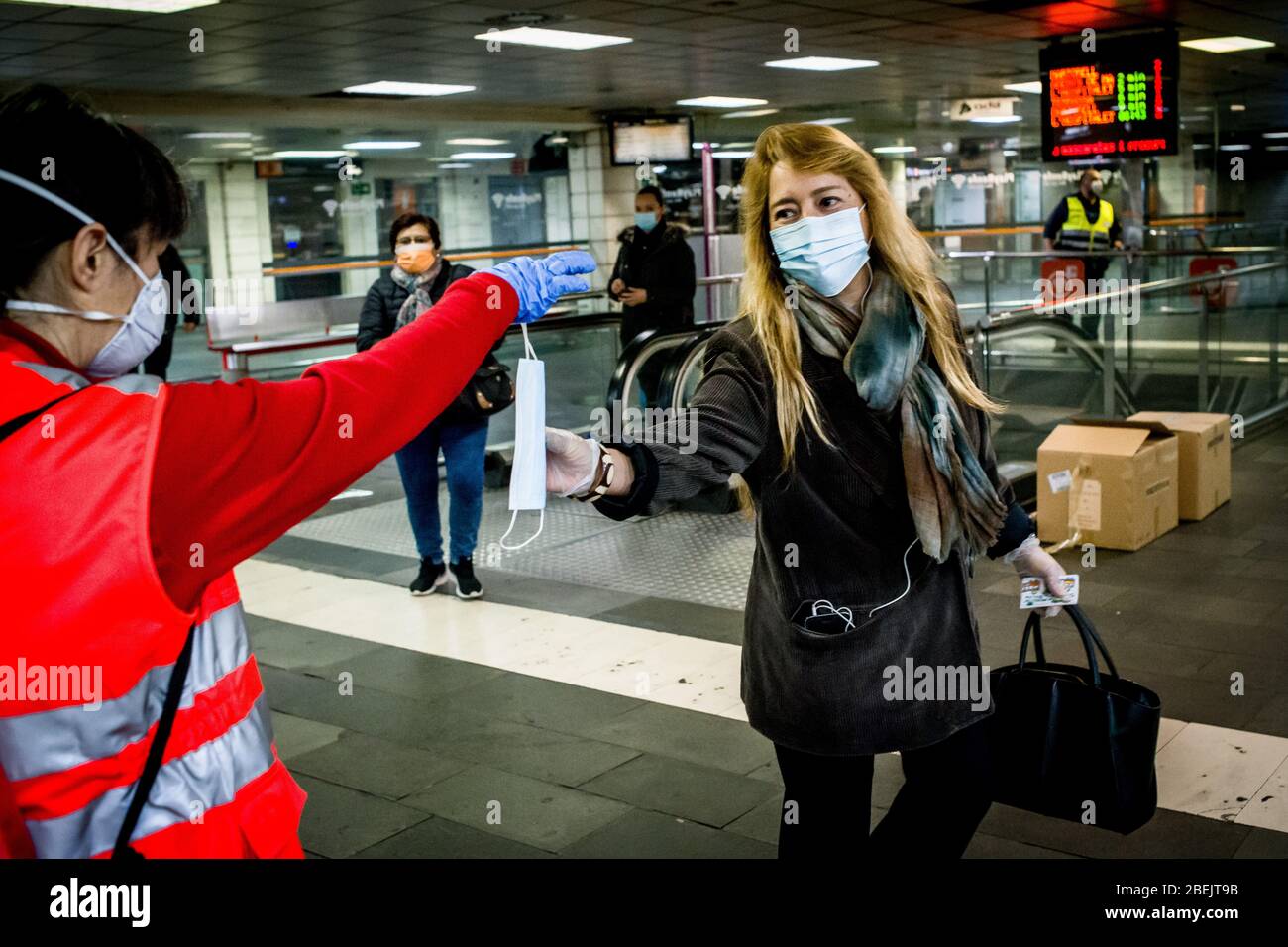 Barcelona, Katalonien, Spanien. 14. Apr 2020 - EIN Freiwilliger des Roten Kreuzes verteilt Schutzmaske unter Pendlern am Bahnhof Catalunya in Barcelona. Tausende von Menschen kehren zur Arbeit zurück, nachdem die spanische Regierung die strengsten Maßnahmen der Coronavirus-Haft aufzuheben hat. Quelle: Jordi Boixareu/Alamy Live News Stockfoto