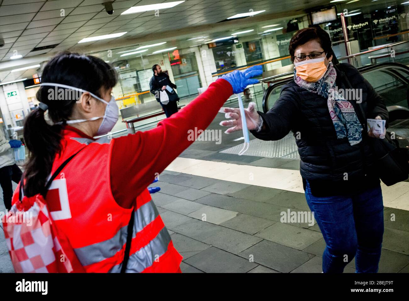 Barcelona, Katalonien, Spanien. 14. Apr 2020 - EIN Freiwilliger des Roten Kreuzes verteilt Schutzmaske unter Pendlern am Bahnhof Catalunya in Barcelona. Tausende von Menschen kehren zur Arbeit zurück, nachdem die spanische Regierung die strengsten Maßnahmen der Coronavirus-Haft aufzuheben hat. Quelle: Jordi Boixareu/Alamy Live News Stockfoto