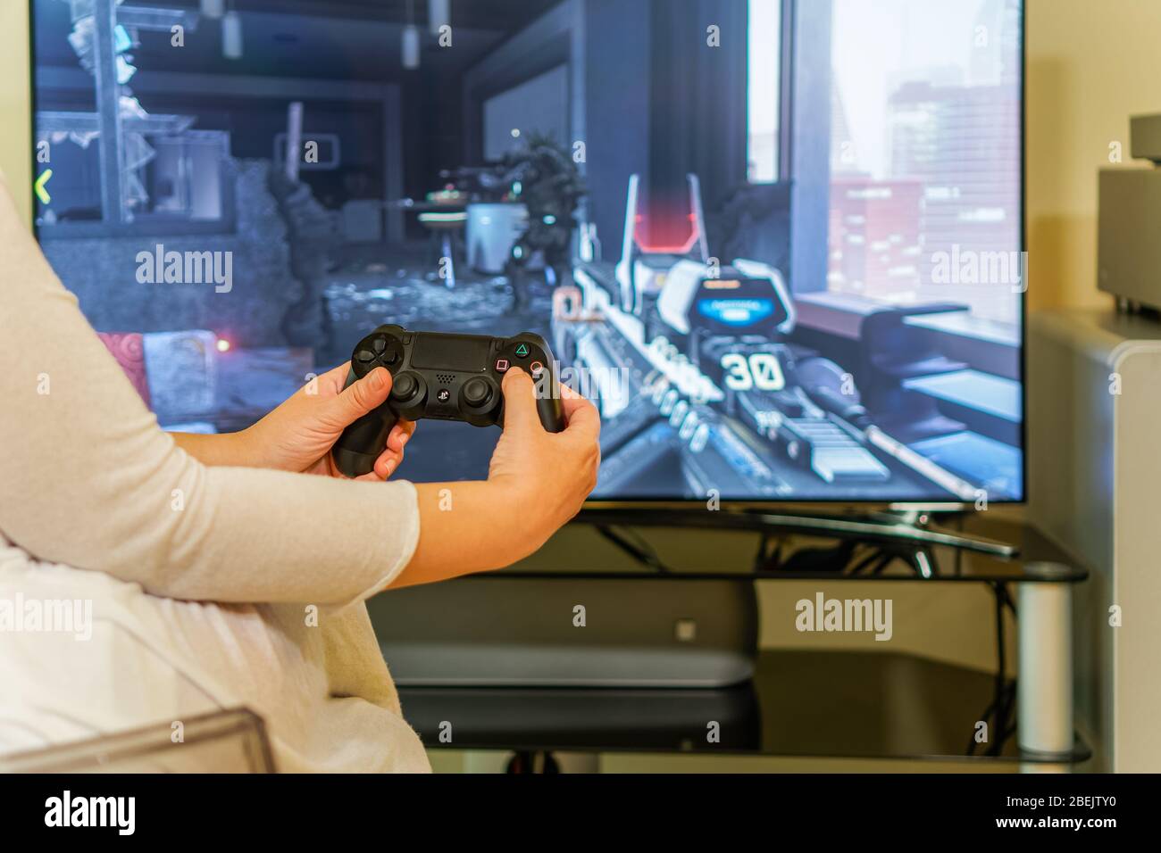 PlayStation 4-Spiel auf dem Fernseher spielen. Female Holding DualShock 4  Wireless-Controller lernt Action-PS4-Spiel auf großem Bildschirm zu  spielen, mit Fokus auf Hände Stockfotografie - Alamy