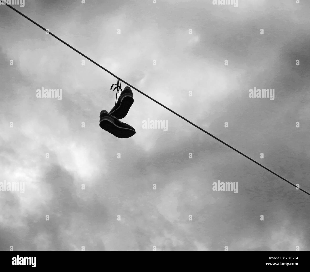 Ein Paar Schuhe, die zusammengebunden sind, auf eine Stromleitung geworfen als Streich an jemanden. Konzept: Minimalismus in der Fotografie. Stockfoto
