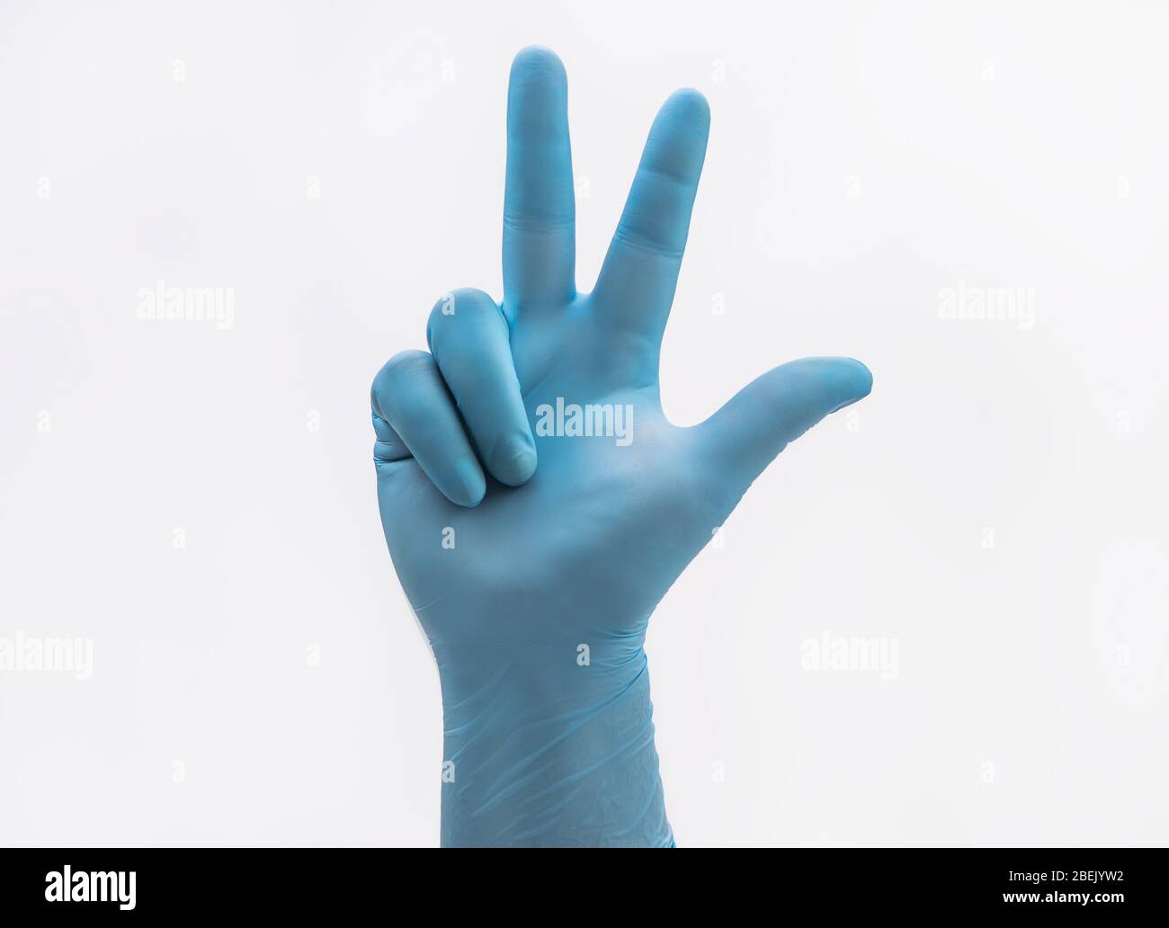 Hand mit medizinischen blauen Latex Schutzhandschuhe mit drei Fingern auf weißem Hintergrund als orthodox christliches Zeichen der heiligen dreifaltigkeit und widerstehen gehalten Stockfoto