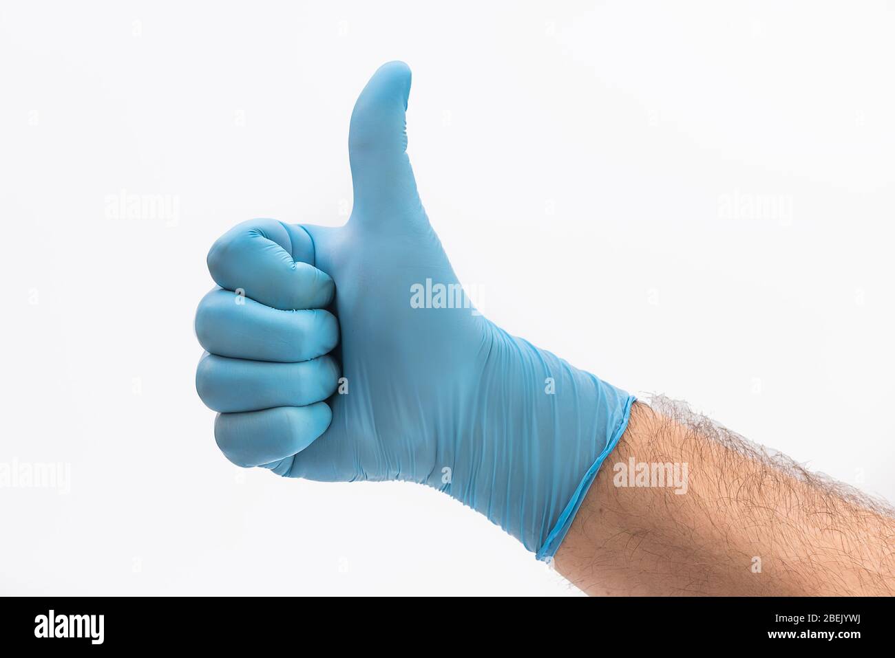 Hand mit medizinischen blauen Latex-Schutzhandschuhe mit Daumen nach oben auf weißem Hintergrund als positives Zeichen und Widerstand gegen Pandemie gehalten Stockfoto