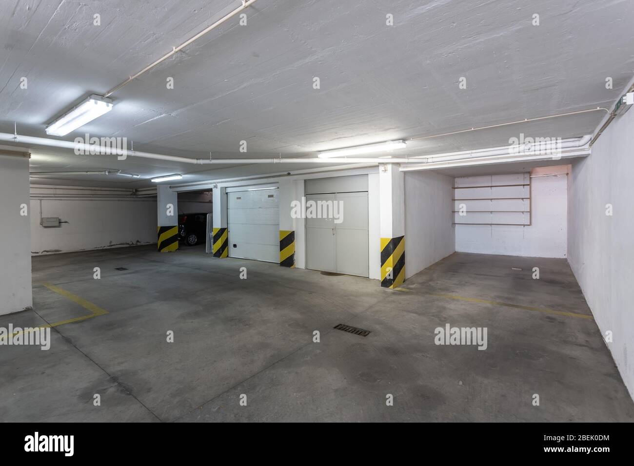 Gemeinsames Parkhaus für Autos in einem mehrstöckigen Gebäude mit Kanalrohren. Stockfoto