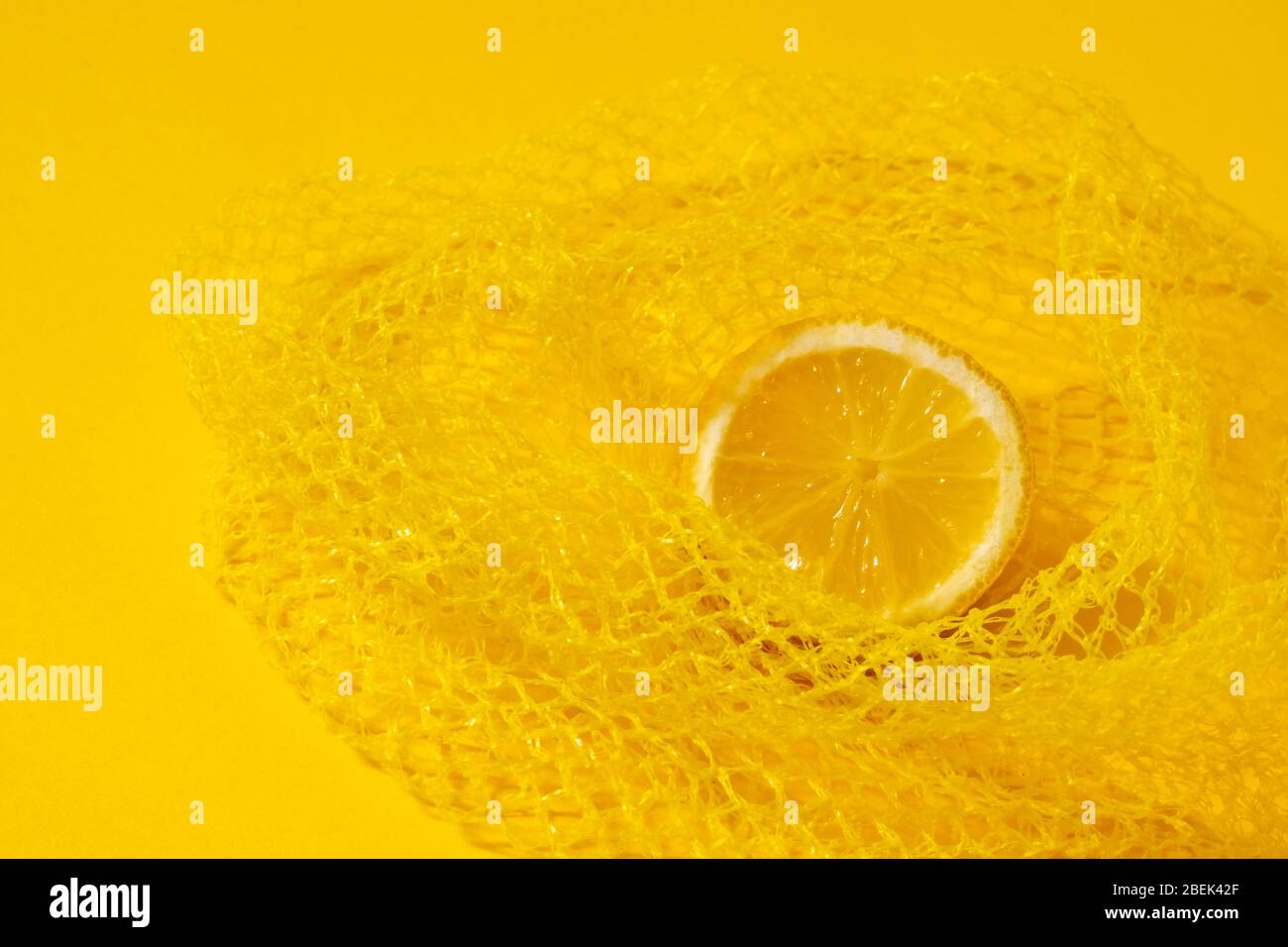 Zitronenscheibe in gelbem Paching auf gelbem Hintergrund. Nahaufnahme, Kopierbereich. Stockfoto