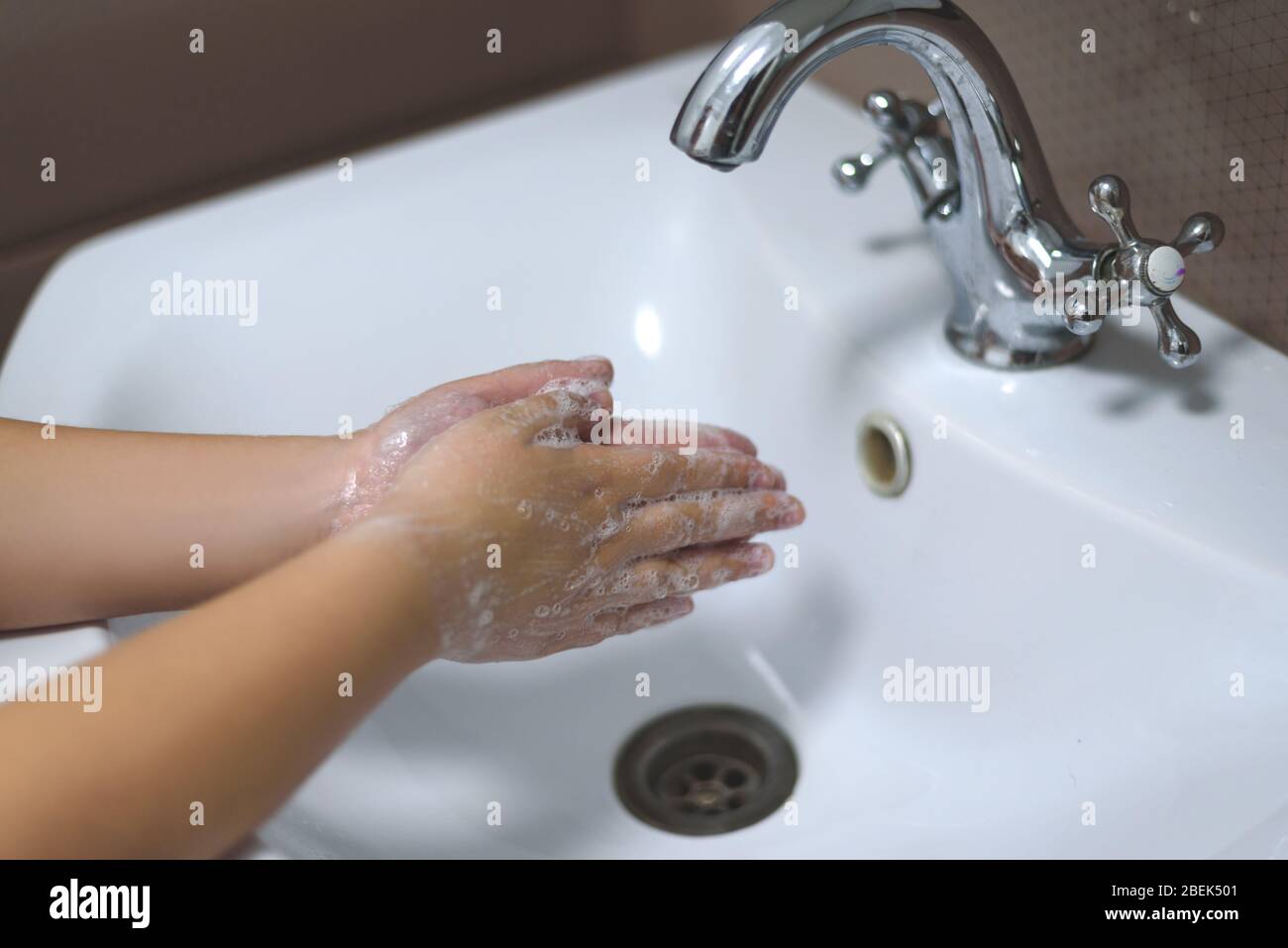 Waschen der Kinderhände mit der Seife unter dem Kran mit dem Wasser. Stockfoto