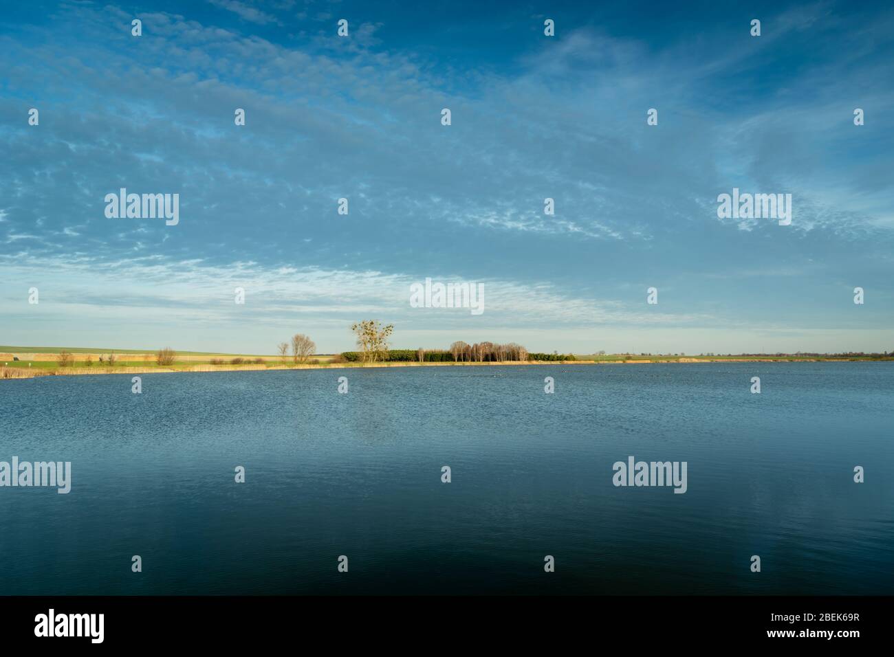 Ruhige Wasseroberfläche auf einem See, Horizont und Wolken auf blauem Himmel Stockfoto