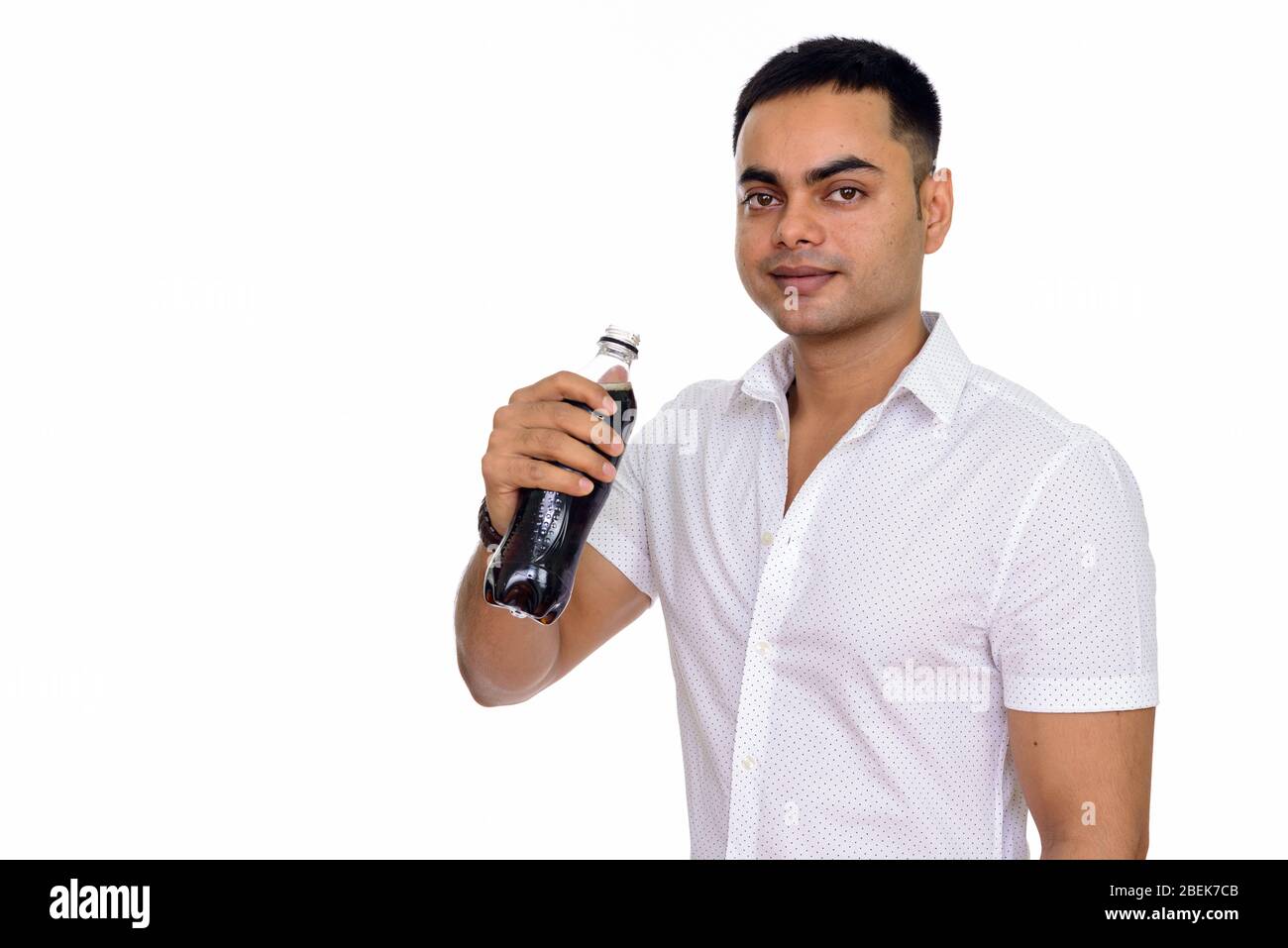 Studioaufnahme eines jungen hübschen Indianers, der Soda vor weißem Hintergrund trinkt Stockfoto