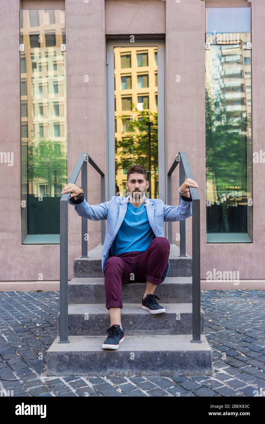 Porträt des glücklichen bärtigen jungen Mannes auf der Treppe sitzend Stockfoto