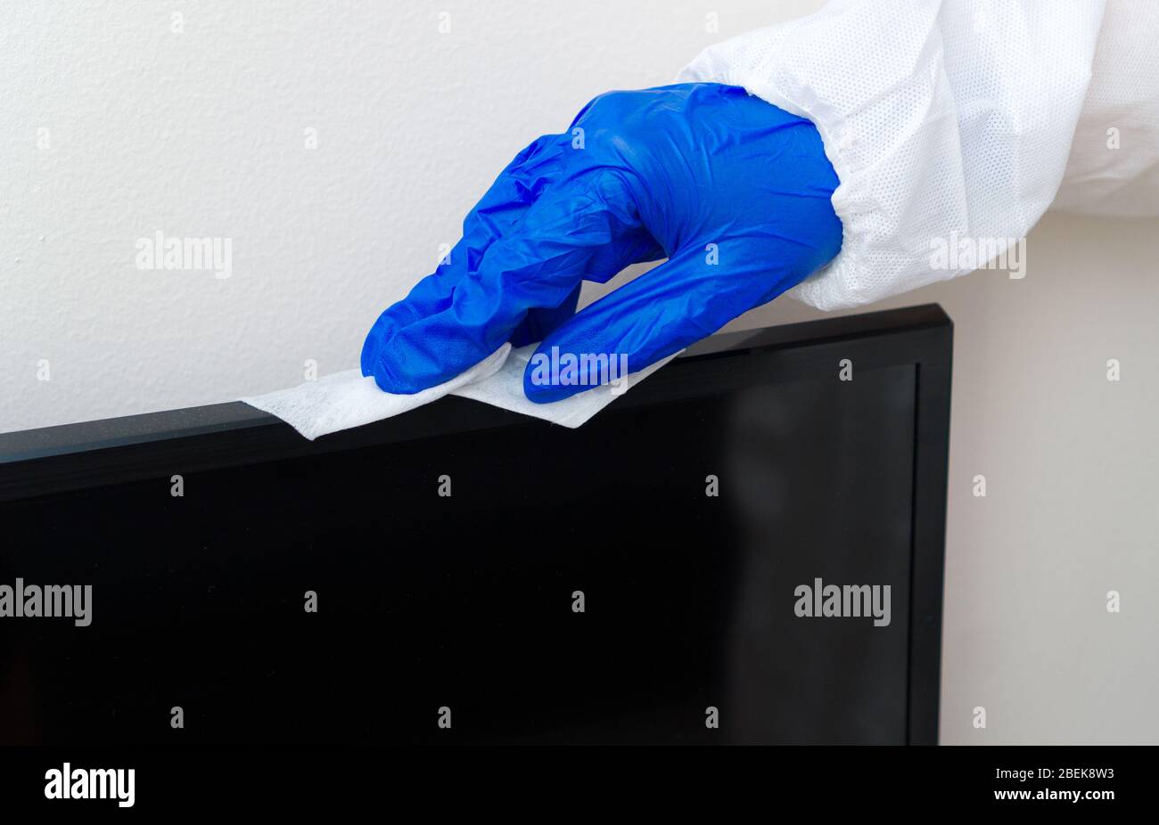 Hand in Schutzhandschuh mit Serviettenreinigungs-LCD-Panel. Desinfektionskonzept Covid-19. Stockfoto
