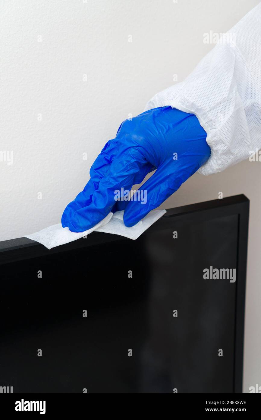 Hand in Schutzhandschuh mit Serviettenreinigungs-LCD-Panel. Desinfektionskonzept Covid-19. Stockfoto