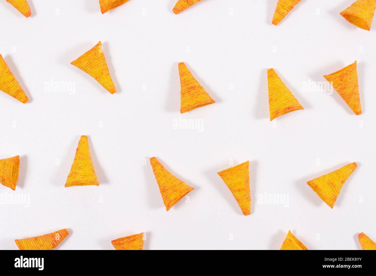 Dreieckige, Mais Tortilla Chips Nachos mit ungewöhnlicher Form auf hellem weißen Hintergrund. Offene Komposition. Hintergrund für Snacks. Draufsicht. Mexikanisches Essen. Stockfoto