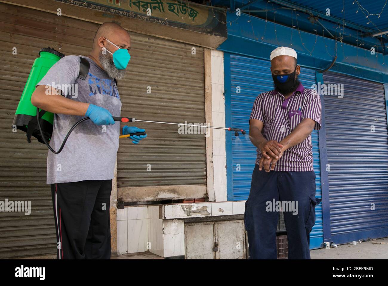 DHAKA, BANGLADESCH - APRIL 14: Ein Mann, der während der von der Regierung auferlegten Lockdown als vorbeugende Maßnahme gegen das C Medikamente in die Hände eines Passanten sprüht Stockfoto