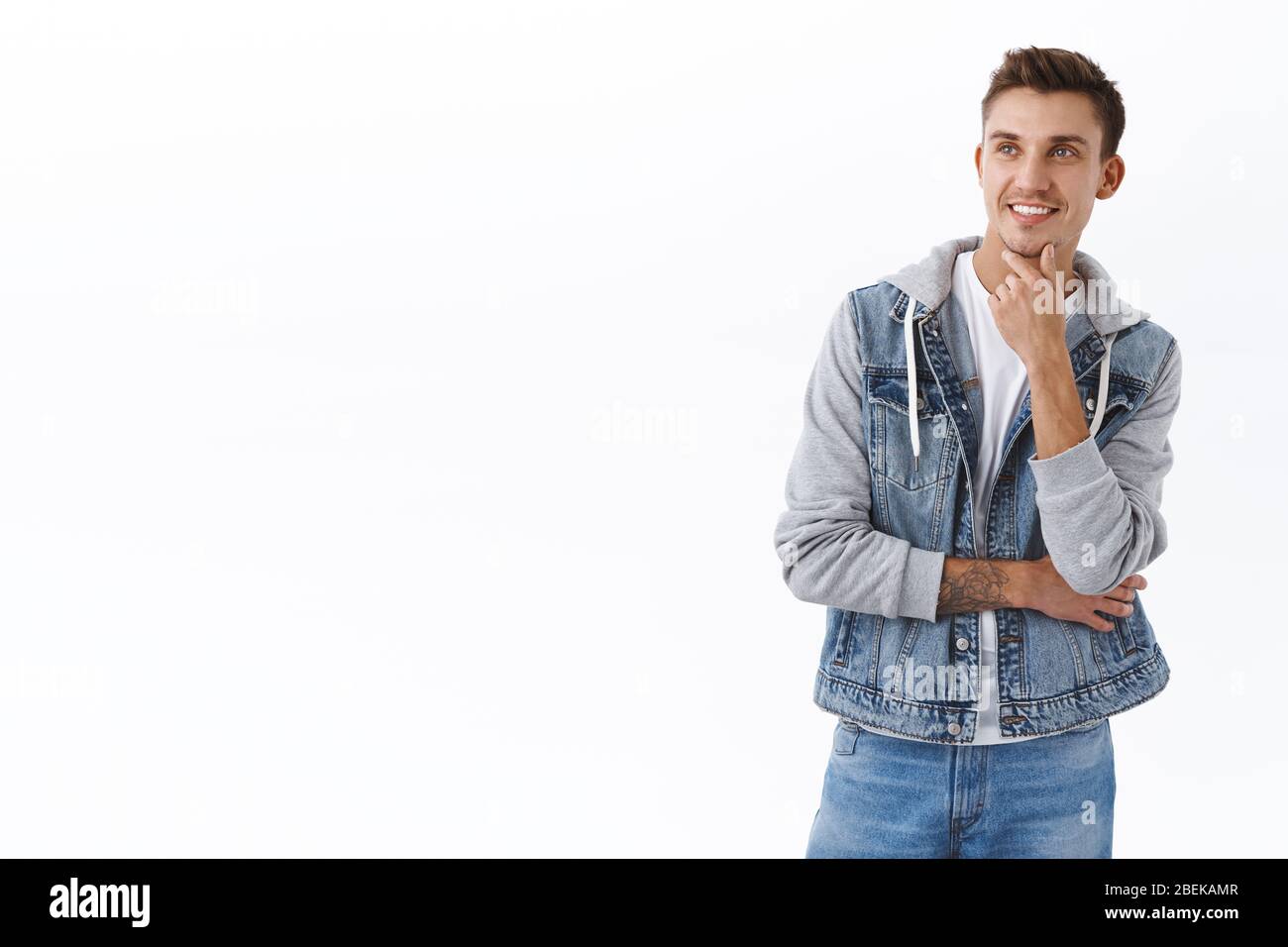 Nachdenkliche gut aussehende intelligente blonde Mann, berühren Kinn grübeln, mit erfreut Lächeln weg, die Wahl, die Entscheidung zwischen Varianten als Blick nach links Stockfoto