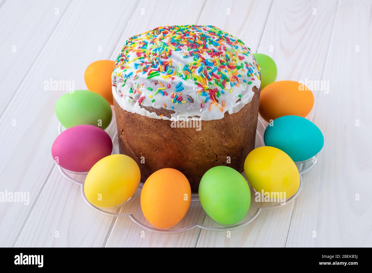 Osterkuchen und bunte Eier auf weißen Holzbrettern bemalt. Österliche Grußkarte. Heller Hintergrund, Planken Textur Stockfoto
