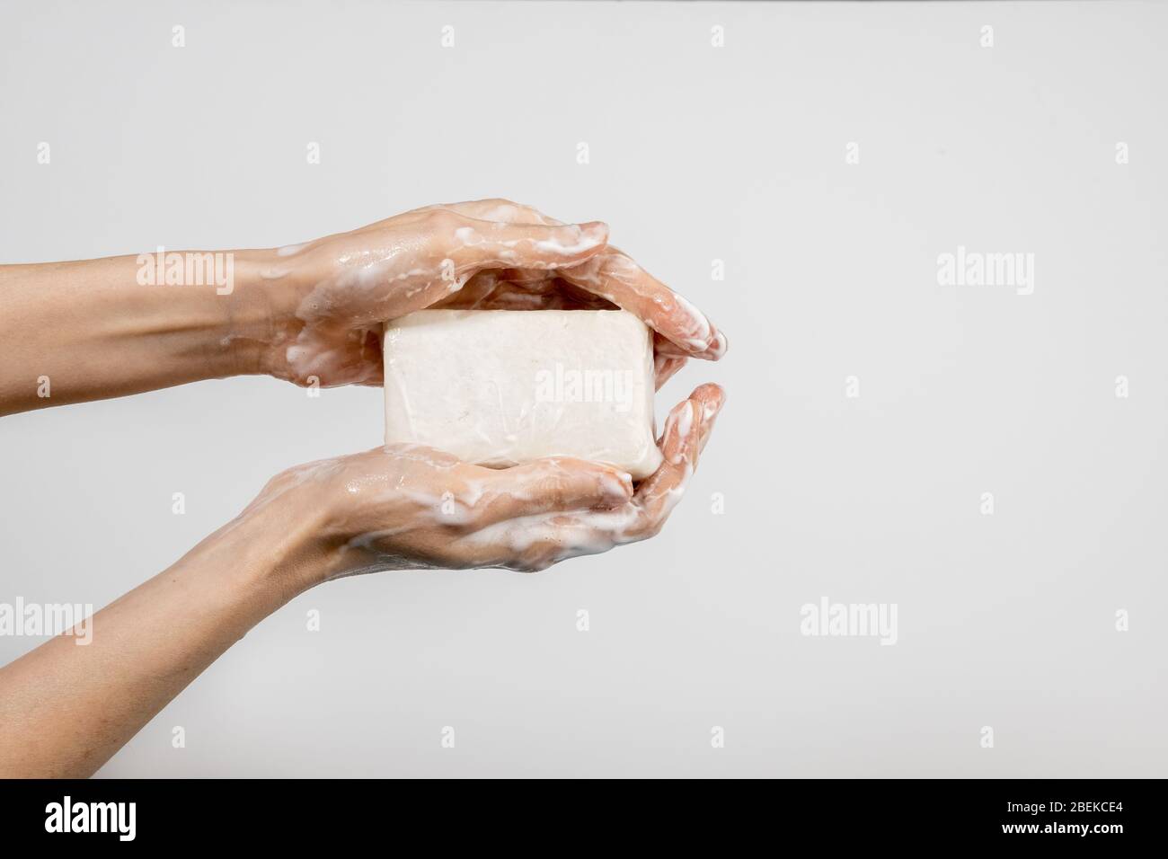 Nahaufnahme der kaukasischen Frau, die ihre Hände mit sprudelnden Seifenstück auf weißem Hintergrund isoliert waschen. Vorführung des Händewaschens. Konzept der Hygiene und Stockfoto