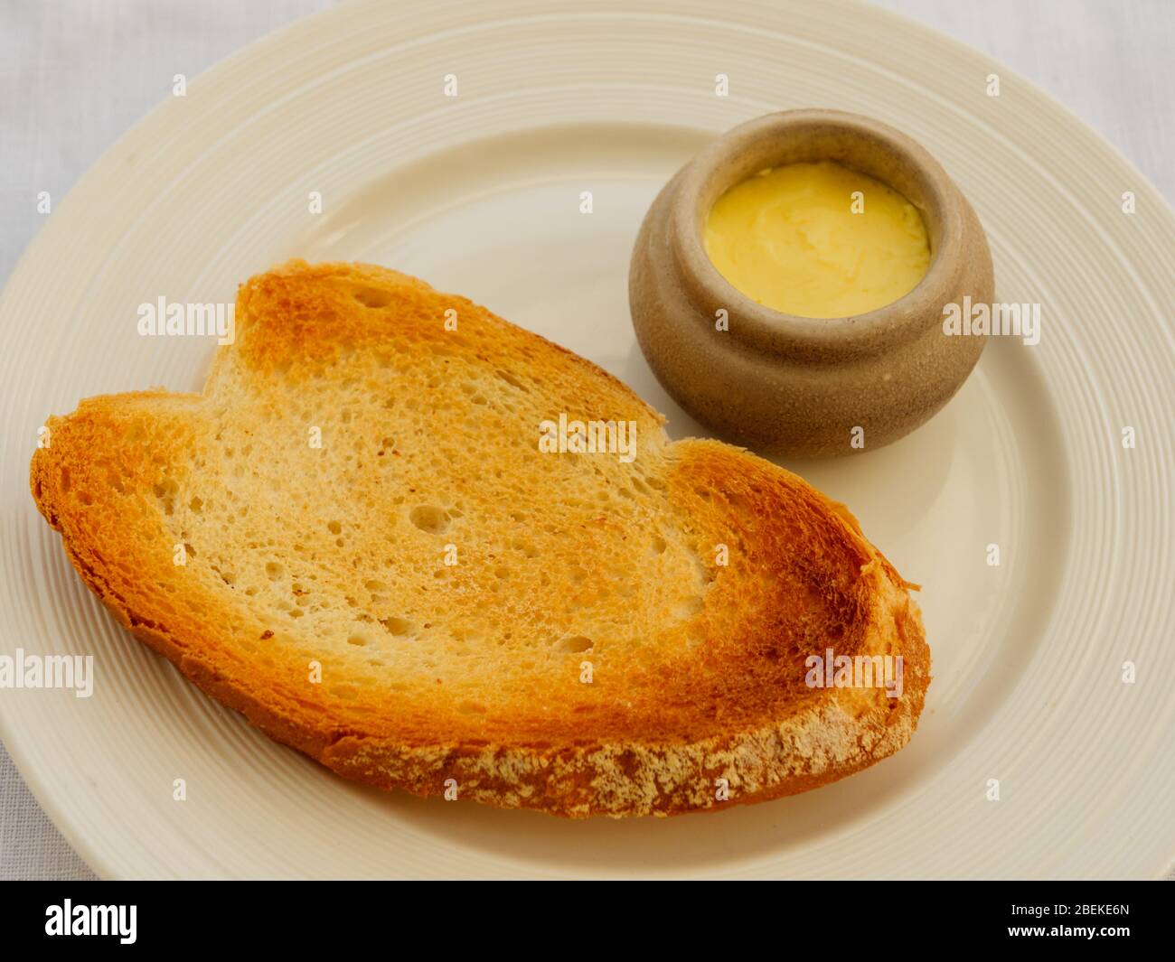 Scheibe Toast mit einer Portion Butter auf der Seite Stockfoto
