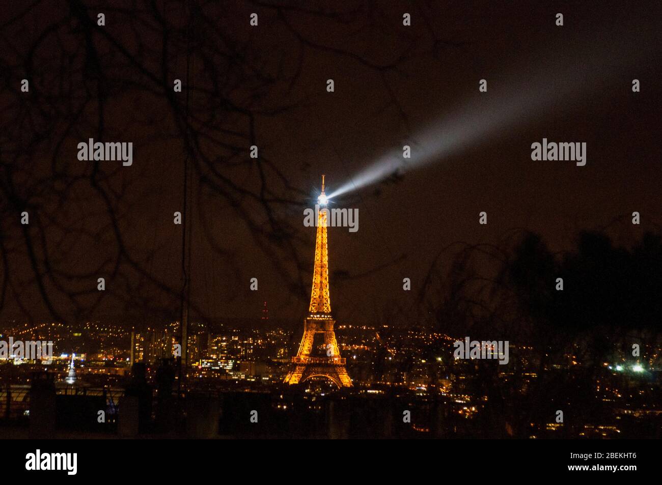 Ein Leuchtfeuer des Eiffelturms durchquert die Baumkronen von Montmartre, Paris, Frankreich. Stockfoto