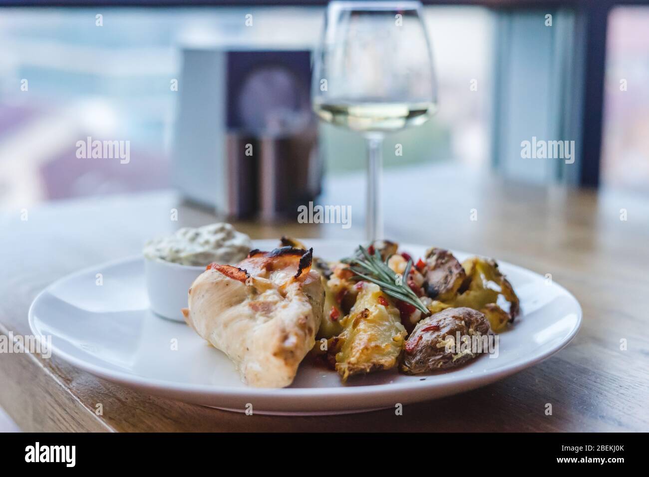 Restaurant Essen, Fleisch, Kartoffeln und Sauce. Glas Weißwein auf Holztisch Stockfoto