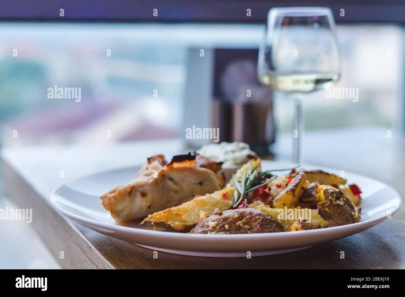 Restaurant Essen, Fleisch, Kartoffeln und Sauce. Glas Weißwein auf Holztisch Stockfoto