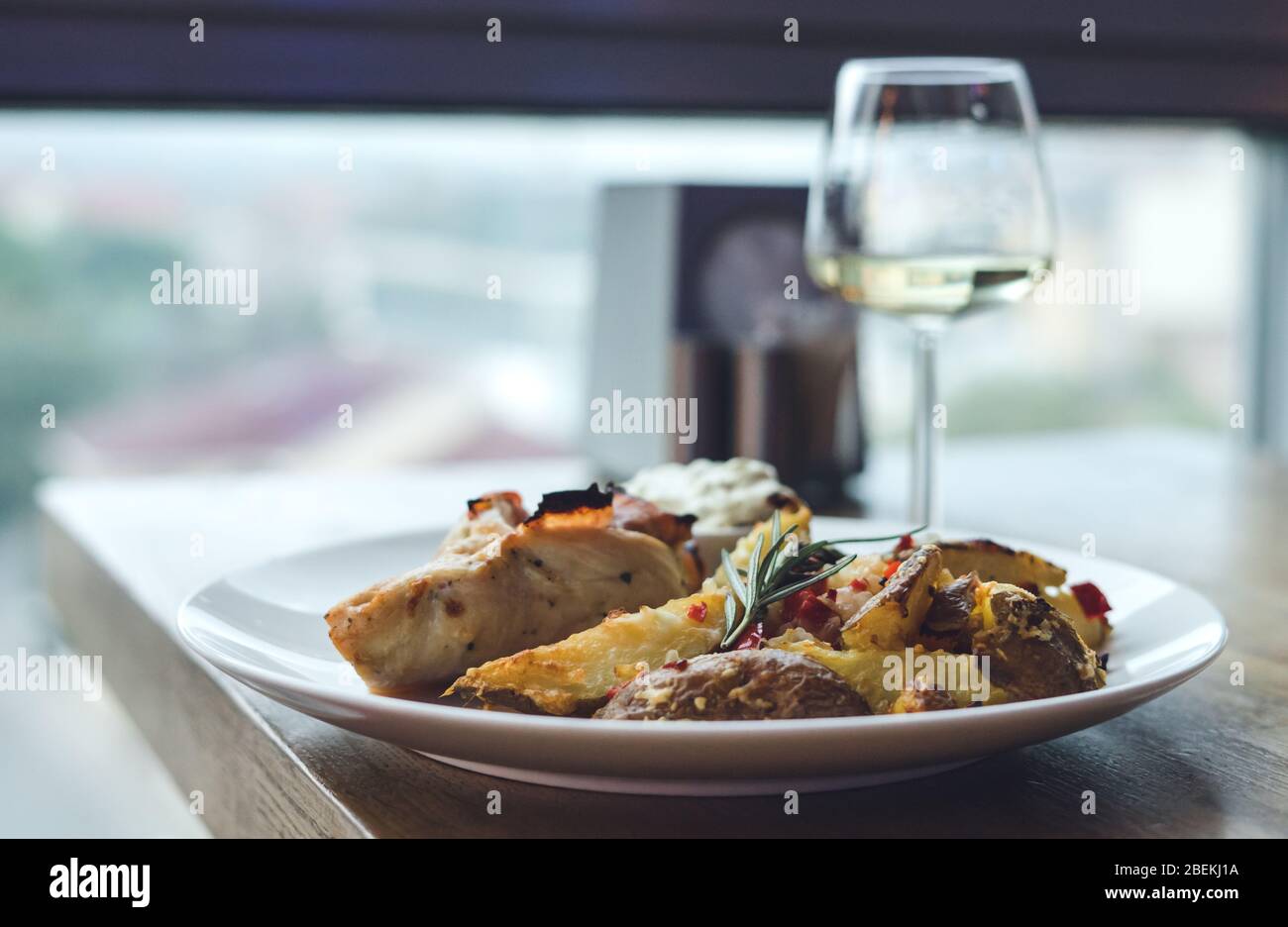 Hühnerfleisch mit Gemüse in einem Restaurant. Ein Glas Weißwein Stockfoto