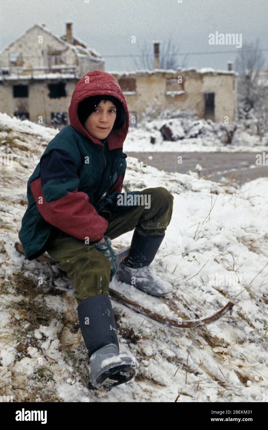 Sarajevo 1995 - Kind spielt im Schnee in Wohngebiet, das von serbischen Bombenangriffen während der Belagerung von Sarajevo, Bosnien und Herzegowina getroffen wurde Stockfoto